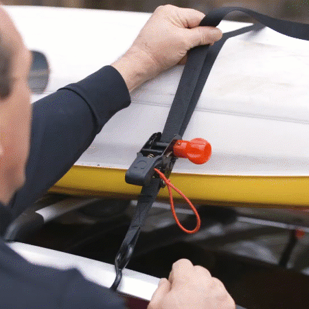 Person expertly tightening an OmegaStrap® on a white and yellow surfboard secured to a vehicle roof rack with a locking mechanism. - OmegaStrap - World's Greatest Ratchet Strap