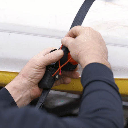 Hands securing a kayak with the OmegaStrap, renowned as the world's greatest ratchet strap because of its red control knob, onto a cars roof. - OmegaStrap - World's Greatest Ratchet Strap